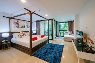 a bedroom with a canopy bed and a blue rug at the Kris Bangtao Phuket not in laguna area in Laguna Phuket