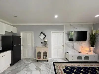 a kitchen with white cabinets and a flat screen tv at Green place condominium in Ban Lo Long