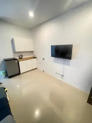 a room with a kitchen with a tv on the wall at Nai-harn Apartments in Phuket Town