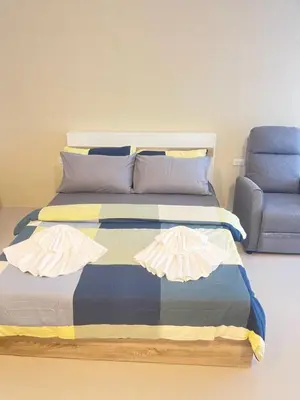 a bed in a room with a blue chair at Nai-harn Apartments in Phuket Town