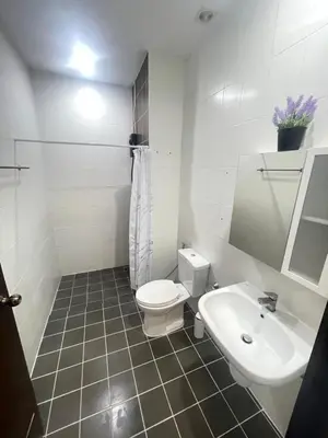 a white bathroom with a toilet and a sink at Nai-harn Apartments in Phuket Town