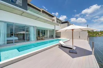 an umbrella and a chair next to a swimming pool at Beachfront residence - just a step from the beach in Laguna Phuket