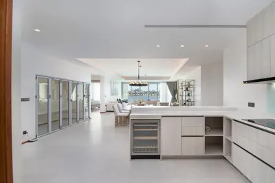 a kitchen with white counters and a living room at Beachfront residence - just a step from the beach in Laguna Phuket