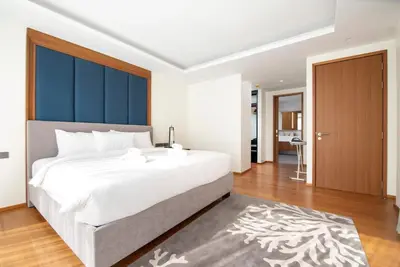 a bedroom with a large white bed with a blue headboard at Beachfront residence - just a step from the beach in Laguna Phuket