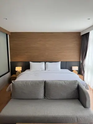 a bedroom with a large bed with a couch at Apartment Naithon Wyndham in Nai Thon Beach