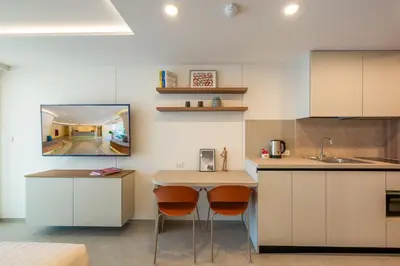 a kitchen with white cabinets and a counter with two stools at HOMA Chalong Bay in Ban Klang