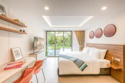a bedroom with a large bed and a desk and chairs at HOMA Chalong Bay in Ban Klang