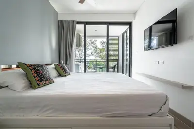 a bedroom with a large white bed and a balcony at 1Bdr in Cassia Residence Laguna in Laguna Phuket