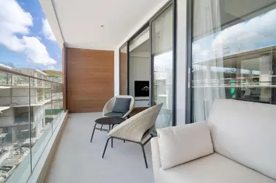an apartment with a balcony with a couch and chairs at Beachfront 1 Bedroom 361 Condo Kora Resort in Phuket Town