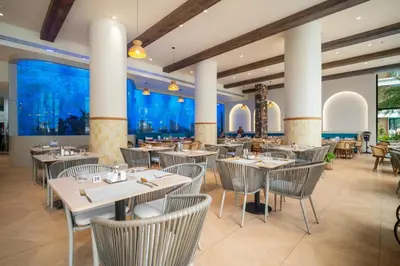 a restaurant with tables and chairs and large windows at Kora Beachfront 240 One Bedroom Apartment Phuket in Phuket Town