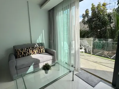 a living room with a couch and a glass table at Modern 1 Bedroom Apartment - At The Tree Rawai in Rawai Beach