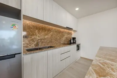 a kitchen with a sink and a refrigerator at Suite Melos 2BR Pool Gym Access Ozone in Laguna Phuket