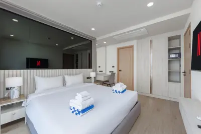 a bedroom with a large white bed and a desk at Suite Melos 2BR Pool Gym Access Ozone in Laguna Phuket