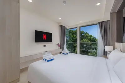 a white bedroom with a large bed and a large window at Suite Melos 2BR Pool Gym Access Ozone in Laguna Phuket