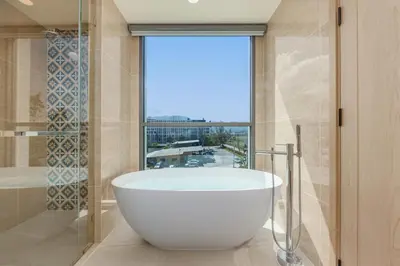 a bath tub in a bathroom with a large window at Suite Melos 2BR Pool Gym Access Ozone in Laguna Phuket