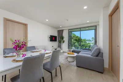 a kitchen and living room with a table and chairs at Suite Melos 2BR Pool Gym Access Ozone in Laguna Phuket