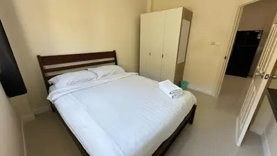 a bedroom with a bed with white sheets and a cabinet at Holiday home in Ban Na Khua