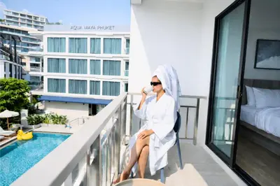 a woman sitting on a balcony next to a pool at Aqua Maya Phuket in Patong Beach