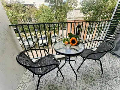 a table and two chairs on a balcony with a bowl of fruit at Cozy 1BR Tropical View at Title in Nai Yang Beach