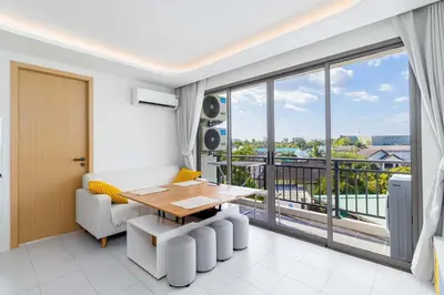 a living room with a table and a balcony at C256 2BR Stay Close to Beach Rooftop Pool Views in Kamala Beach