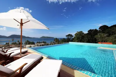 a swimming pool with chairs and an umbrella at Beachfront Patong Hillside Modern Apartment in Patong Beach
