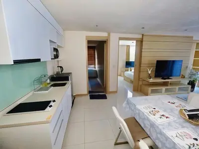 a kitchen and a living room with a table at Beachfront Patong Hillside Modern Apartment in Patong Beach