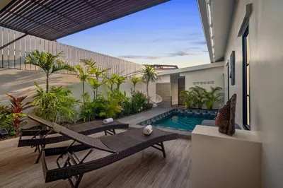 a balcony with a pool and chairs and a house at Modern Zen Oasis in Phuket in Ban Saiyuan (1)