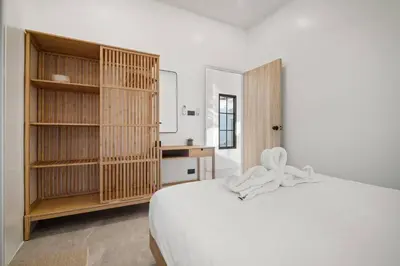 a bedroom with a white bed and a wooden book shelf at Modern Zen Oasis in Phuket in Ban Saiyuan (1)