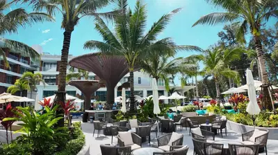 a hotel patio with chairs and palm trees at Premier Pool View Studio 348 Kora Resort in Phuket Town