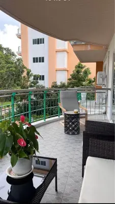a balcony with chairs and a table with a vase of flowers at Phuket 604 in Phuket Town