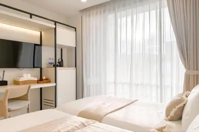 a bedroom with two beds and a desk and a window at Tatami Hotel Phuket in Ban Ket Ho