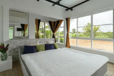 a bedroom with a large white bed and windows at The Garden Escape Villa, Private Tropical Hideaway in Rawai Beach