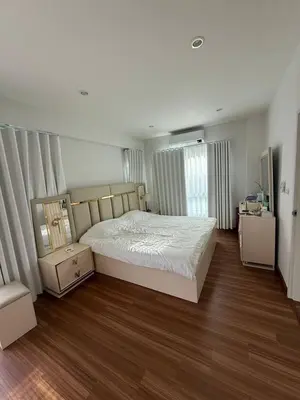 a bedroom with a white bed and a wooden floor at La Perla Residence in Ban Phak Chit