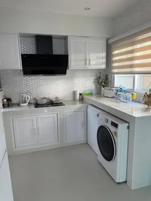 a kitchen with white cabinets and a washing machine at La Perla Residence in Ban Phak Chit