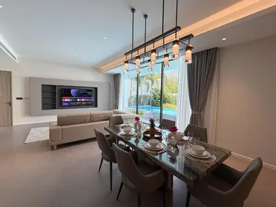 a dining room and living room with a table and chairs at Clover Residence Villa Phuket in Koh Lone