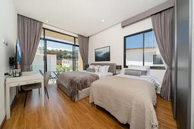 a hotel room with two beds and a desk andwindows at Lelux Villa Kamala - Goldena Twin in Kamala Beach