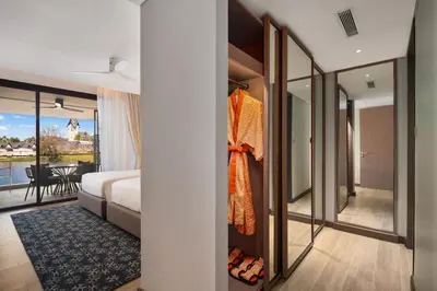 a bedroom with a bed and a room with a balcony at Angsana Oceanview Residences Building 2 in Laguna by Banyan Living in Thalang