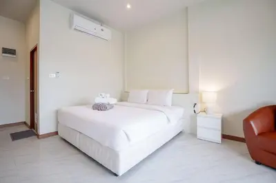 a white bedroom with a white bed and a chair at B201 Banjong Studio 3 Minutes To Nai Harn Beach in Rawai Beach