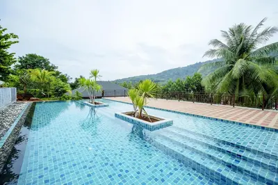 a pool with palm trees and mountains in the background at B203 Banjong Studio 3 Minutes To Nai Harn Beach in Rawai Beach