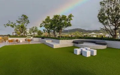 a green lawn with tables and chairs on it at Brand New Premium beachfront apartments! in Bang Tao Beach