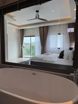 a bathroom mirror with a bed and a bath tub at Santong Villa Rawai in Rawai Beach