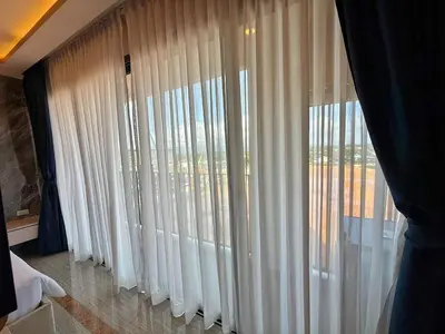 a room with white curtains and a large window at Bellevue Lagoon Phuket in Laguna Phuket