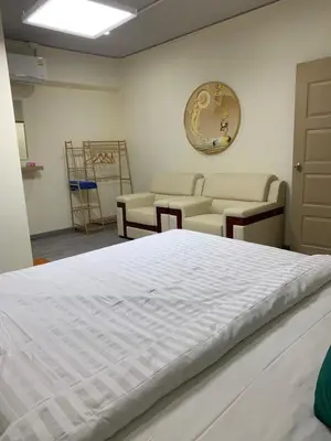 a bedroom with a white bed and a couch at Uncle Yo House in Ban Tha Khreng