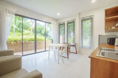 a kitchen with a table and chairs and a kitchen with windows at A102 Banjong 1 Bed apart Near Nai Harn Beach in Rawai Beach