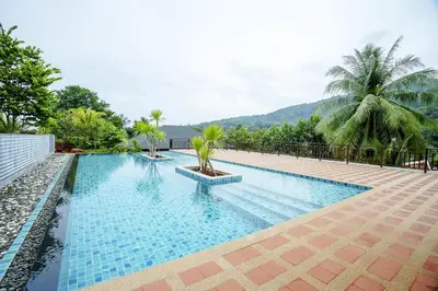 a swimming pool in a resort with trees and mountains at A102 Banjong 1 Bed apart Near Nai Harn Beach in Rawai Beach