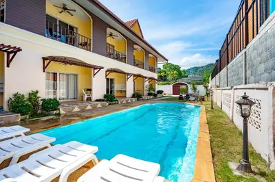 a pool in the backyard of a house with white chairs at Chernin Apartment Suites in Ban Saiyuan (1)