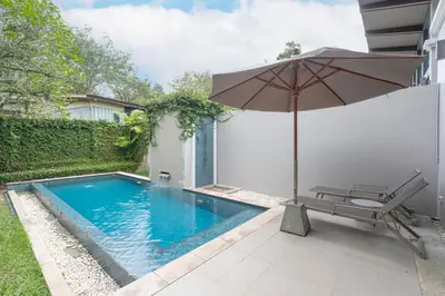 an umbrella and a chair next to a swimming pool at Tropic Escape @ Baan Wana Phuket in Thalang