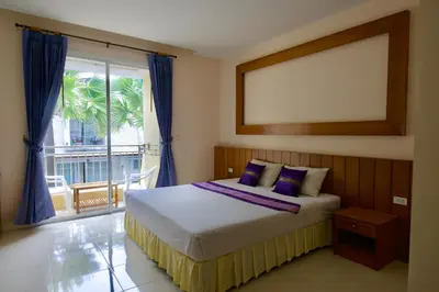 a bedroom with a bed with purple pillows and a window at Ashiraya hostel in Kata Beach
