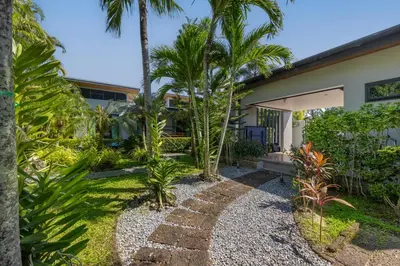a garden with palm trees and a house at Aroha Villa with Private Pool Near Nai Harn Beach in Rawai Beach