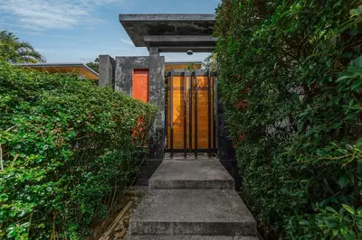 a entrance to a house with a door between two bushes at Aroha Villa with Private Pool Near Nai Harn Beach in Rawai Beach